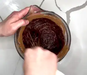 mixing cacao powder into butter, sugar, and eggs mixture